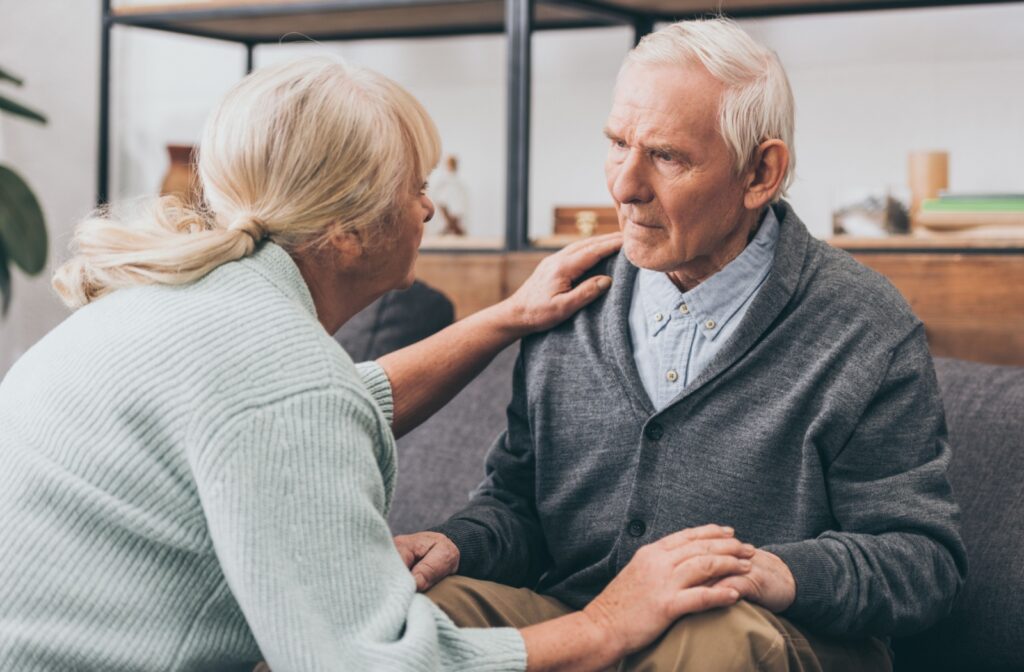 An older woman is comforting her husband who appears to be confused.