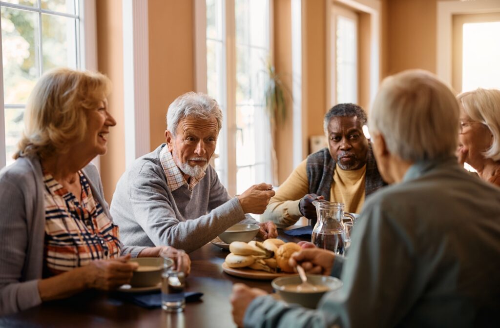 A group of seniors talk over a delicious breakfast in a memory care community.